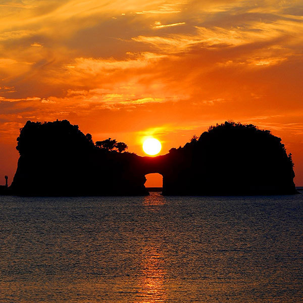 夕日と円月島　真ん中の穴に夕日が入る時期は春分と秋分の前後一カ月ほどといわれております。